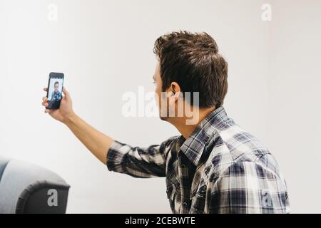 Smiling young man taking selfie on smartphone Stock Photo
