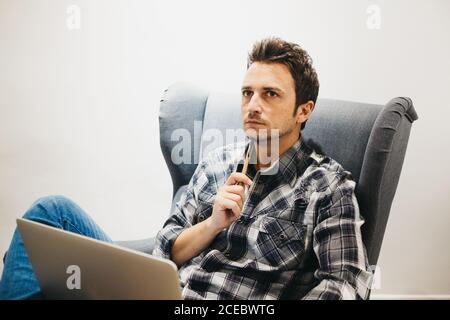 Young man using laptop on armchair Stock Photo