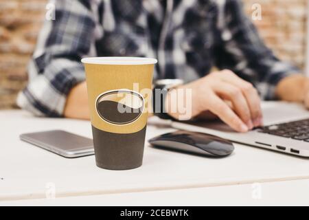 Young man using laptop at table with cup and smartphone Stock Photo