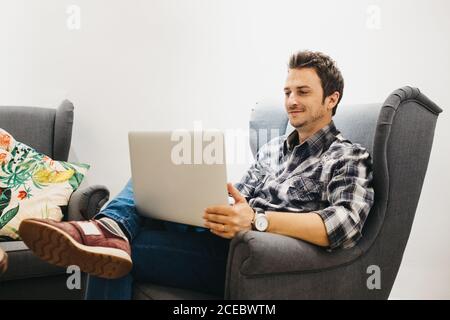 Young man using laptop on armchair Stock Photo