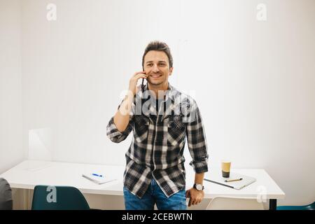 Young man with laptop talking on smartphone Stock Photo