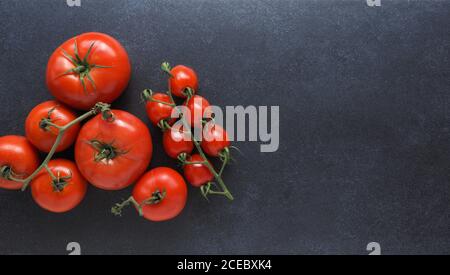 Different organic tomato varieties on a dark stone kitchen table with space for text or image Stock Photo
