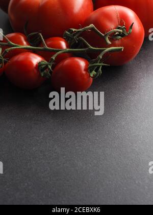 Different organic tomato varieties on a dark stone kitchen table with space for text or image Stock Photo