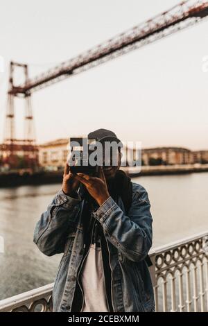 Cheerful man with camera on embankment Stock Photo