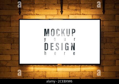 Mockup glowing TV screen at night with white screen on brick wall of modern living room background Stock Photo