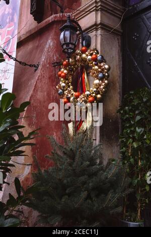 Christmas wreath decorated with gold and red balls, hanging on the outside of the house, old Central European style Stock Photo