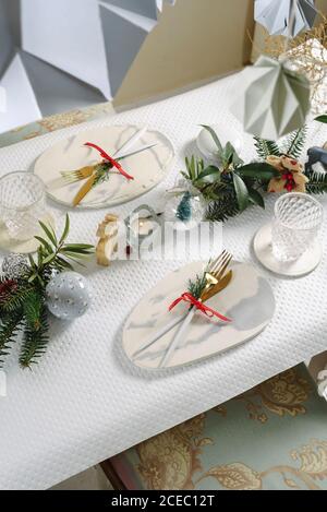 Holiday celebration table setting, in white and gold colors, with hanging decorations decorating the table Stock Photo