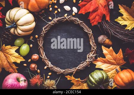 Fall composition for Thanksgiving with a wreath, autumn leaves, pumpkins, hazelnuts, acorn, corn seeds, grapes and pine cones. Overhead view with copyspace Stock Photo