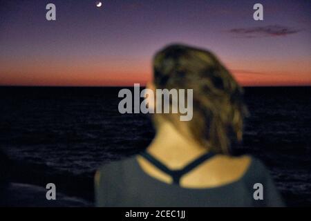 Woman shaking head against night sky and sea Stock Photo
