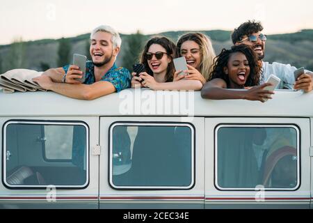 Friends using smartphones in van Stock Photo