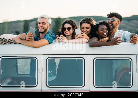 Friends using smartphones in van Stock Photo