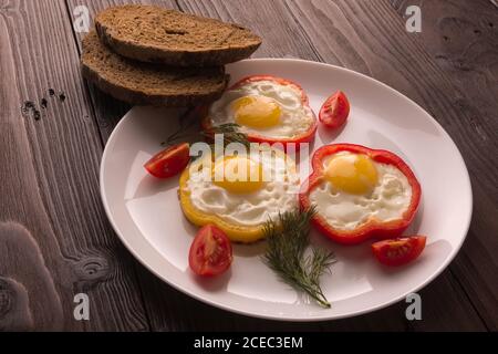 Scrambled eggs fried in rings of Bulgarian pepper with tomatoes and herbs. Stock Photo