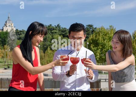 Asian tourists clinking glasses on street Stock Photo