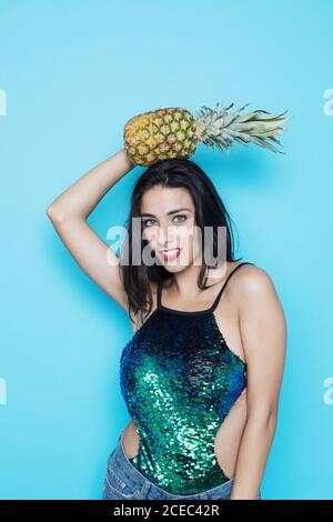 Young Woman posing in studio and holding pineapple Stock Photo