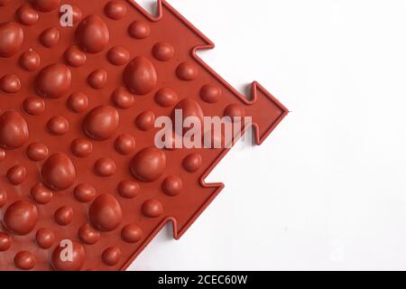 Brown orthopedic mat in the form of small stones on a white background for foot massage. Prevention of children's flat feet Stock Photo