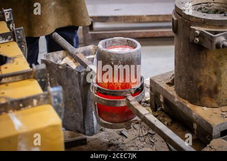 Crop male standing near crucible with molten steel on little foundry Stock Photo