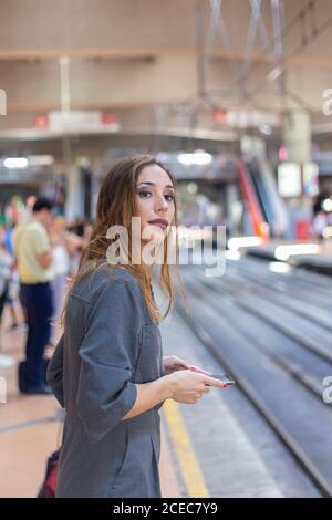 Woman using smartphone on railway station Stock Photo