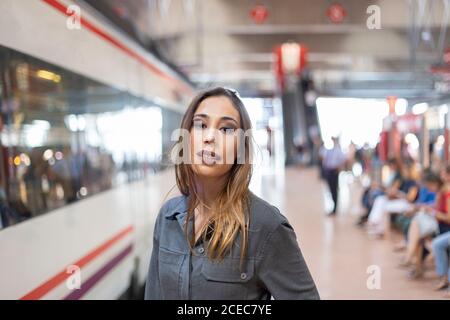 Confident female standing on railway station Stock Photo