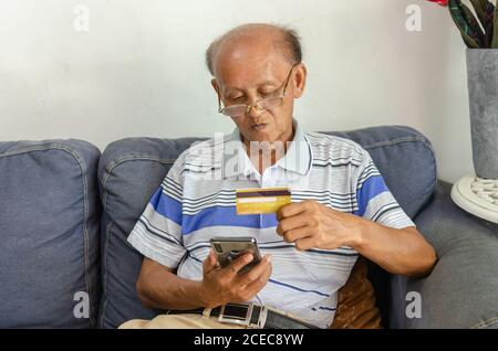 Elderly men watching credit cards and mobile phones on the sofa Stock Photo