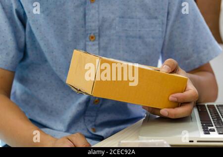 Man hands are holding the parcel hematite and laptop at the table. Stock Photo