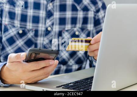 Man Shopping Online Using Laptop With Credit Card.Hands holding credit card and smartphone. Stock Photo