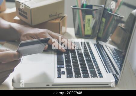 Man's hand holding credit card shopping online with computer. Business online concept. Vintage tone. Stock Photo