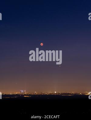 Breathtaking view of red moon over brightly illuminated Madrid during eclipse Stock Photo