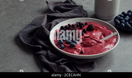 Smoothy of fresh bog blueberries and raspberries in bowl near napkin Stock Photo