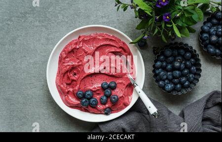 Smoothy of fresh bog blueberries and raspberries in bowl near napkin Stock Photo