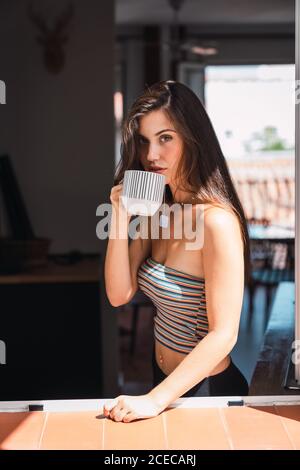 Young Woman drinking coffee near window Stock Photo