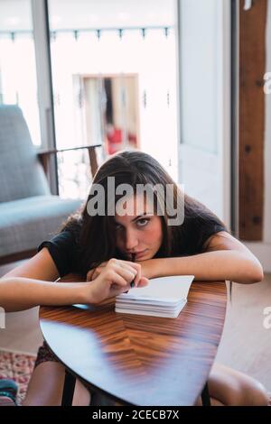 Young Woman sitting in room and writing in diary Stock Photo