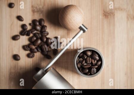 Manual coffee grinder and roasted coffee beans are on wooden desk, flat lay photo with soft focus Stock Photo