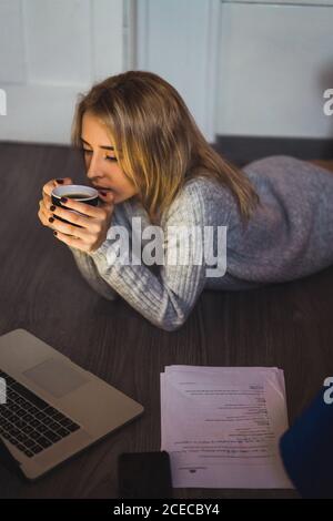 Woman lying on the floor drinking coffee Stock Photo