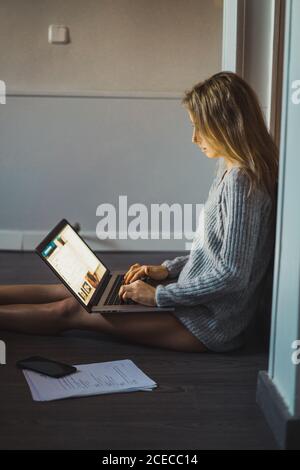 Woman sitting on the floor working with a laptop Stock Photo