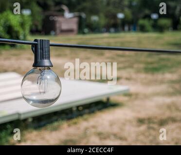 Outdoor light bulb hanging from a wire. Stock Photo