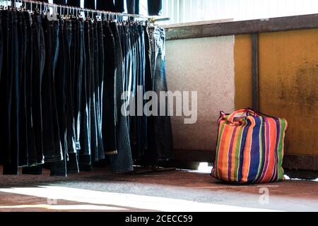 Multi color on Plastic sack and the row of denim pants hanging on trempels. Jeans in clothing store Stock Photo