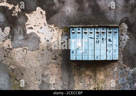 Weathered mailbox hanging on crumbling concrete wall on city street Stock Photo