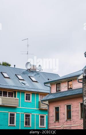 Two building with satellite dishes on roof standing on street of small town against gray sky Stock Photo