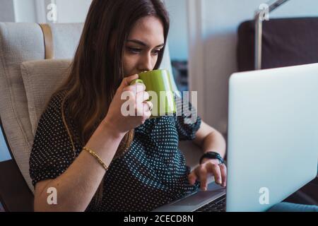 Woman using laptop in armchair Stock Photo