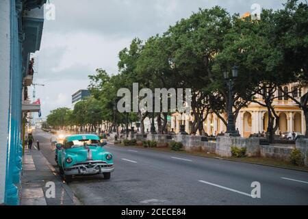 LA HABANA, CUBA - NOVEMBER, 6 , 2018: Vintage automobile on street near old building with blue pillars in Cuba Stock Photo