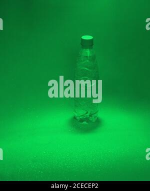 Green plastic water bottle on a green background with water drops Stock Photo