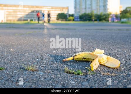 a discarded bitten banana lies on the road in the background of people leaving Stock Photo