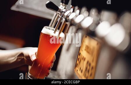 Light beer with large foam in glass against background of bartender Stock Photo