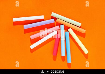 Multicolored thick sticks of chalk on orange background Stock Photo