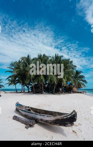 Boat on little island with palms and building between water Stock Photo
