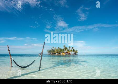 Hammock in ocean, tropical trees and construction between sea and blue sky in San Blas islands, Panama Stock Photo