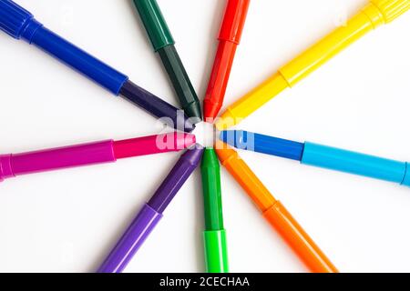 Colored wax crayons for drawing lie in the shape of the sun on a white background. Stock Photo