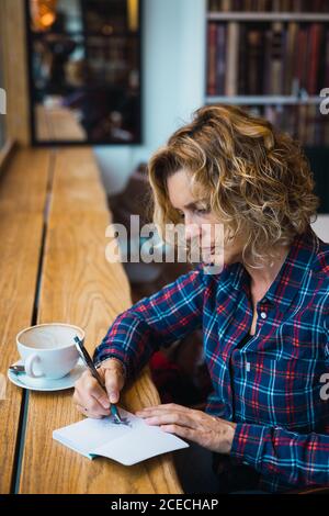 Woman sitting in cafe and writing in notebook Stock Photo