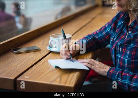 Woman sitting in cafe and writing in notebook Stock Photo