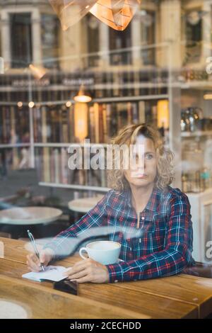 Woman sitting in cafe and writing in notebook Stock Photo